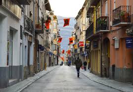 Fontanero Bagà revisando tuberías en una calle empedrada del casco antiguo de Bagà con edificios históricos.