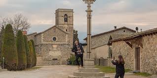 Fontanero Balenyà reparando tuberías cerca del icónico campanario de la iglesia en el centro histórico de Balenyà