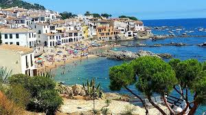 Fontanero Calella calle con fontanero trabajando junto a casas mediterráneas y tiendas locales vibrantes