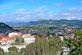 Fontanero Capellades calle estrecha con casas tradicionales y montañas al fondo en un día soleado