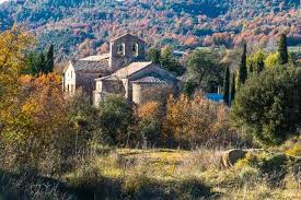 Fontanero Casserres en calle céntrica con casas de piedra y fuente tradicional bajo cielo despejado