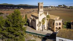 Fontanero Castellví de la Marca en calle adoquinada junto a iglesia histórica local y montañas al fondo