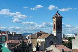 Fontanero Cerdanyola del Vallès camina por la plaza Abat Oliba, rodeado de edificios históricos y tiendas locales.