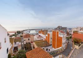 Fontanero El Masnou frente a edificio modernista con azulejos coloridos y palmeras en el paseo marítimo.