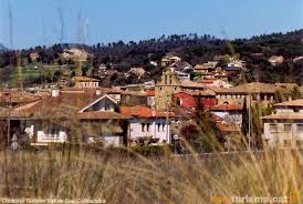 Fontanero Folgueroles: calle adoquinada del casco antiguo con casas de piedra y balcones adornados con flores.