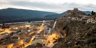 Fontanero Jorba junto a una calle típica con casas de piedra y paisaje montañoso en Jorba.