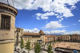 Fontanero Manlleu reparando tuberías en una pintoresca calle con edificios de ladrillo rojo en el centro de la ciudad.