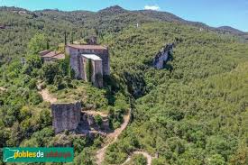 Fontanero Mediona viendo el castillo medieval con un fondo de montañas y casas típicas de piedra.