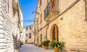 Fontanero Pujalt: calle empedrada con casas de piedra y fuente central, típica en el encantador pueblo catalán.