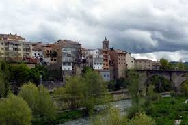 Fontanero Roda de Ter, calle pintoresca con casas de piedra y una iglesia histórica al fondo.