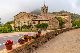 Fontanero Santa Maria de Besora en una calle pintoresca con casas tradicionales de piedra y montañas de fondo