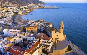Fontanero Sitges trabajando cerca de la iglesia de Sant Bartomeu y Santa Tecla con vistas al mar y calle empedrada.