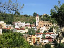 Fontanero Torrelles de Llobregat trabajando cerca de la iglesia parroquial con fondo de montañas y casas típicas.