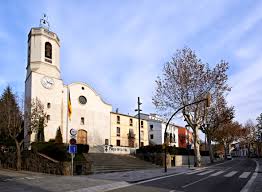 Fontanero Vallgorguina ajustando cañería en calle típica con edificios de piedra y entorno rural pintoresco.