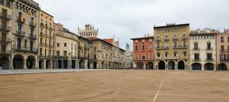 Fontanero Vic reparando tubería en calle histórica con arquitectura típica de Vic, Cataluña.